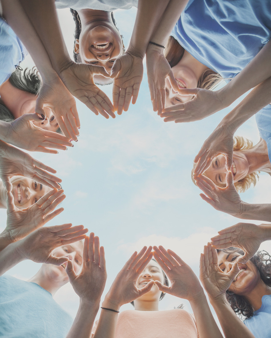 Volunteers standing in a circle with hands shaping hearts