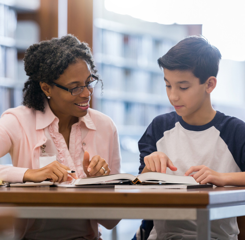 Tutor with student in library reviewing schoolwork