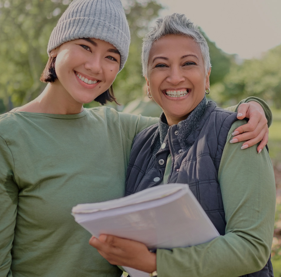 Young asian woman with arm around older hispanic woman outdoors