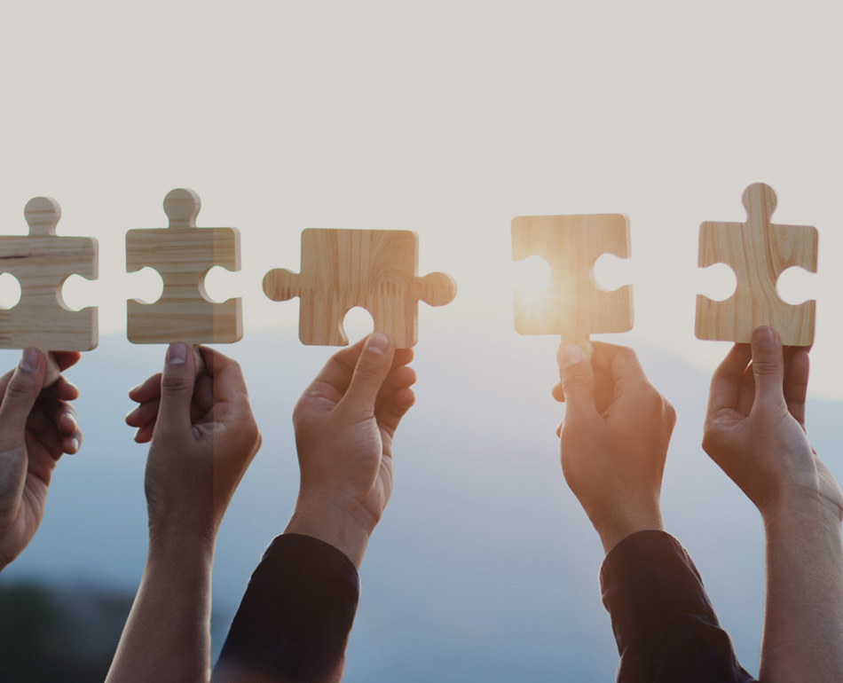 Hands holding large puzzle pieces with lens flare from sky