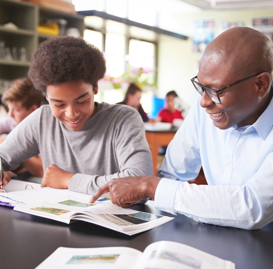 Volunteer sitting with make student reviewing classroom book