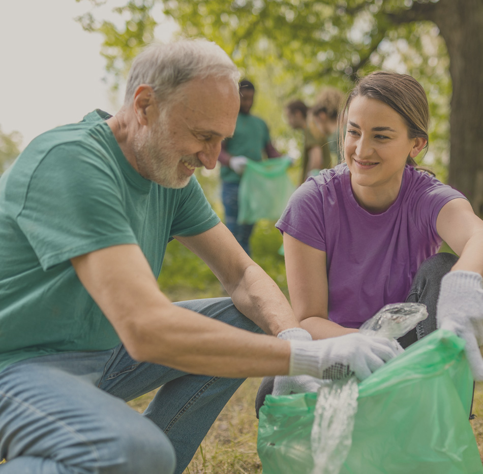 Older volunteer with younger volunteer cleaning up garbage